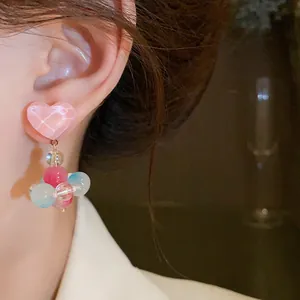 Close-up detail of sweet colorful glass heart dangle earrings worn on a model ear