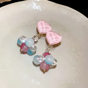 Close-up detail of colorful heart-shaped glass bead drop earrings on a ceramic plate