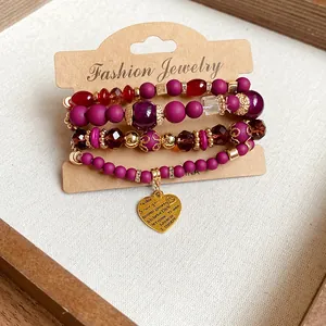 Close-up of multi-strand beaded bracelet with engraved heart pendant on a display card