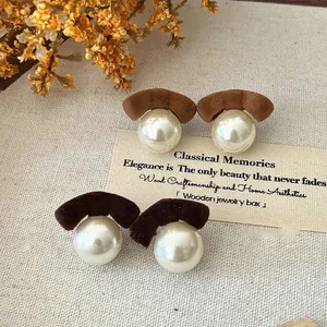 Close-up detail of elegant flocking pearl stud earrings in warm autumn brown shades