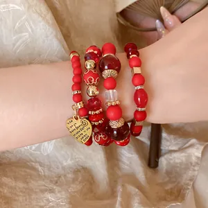 Close-up detail of red beaded bracelet set with multi-language heart charm.
