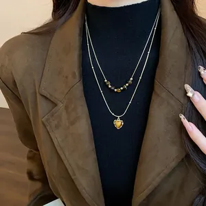 Elegant double layered tiger's eye bead necklace featuring a heart pendant on a model