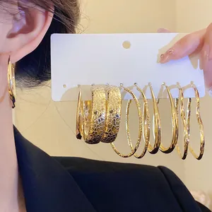 Close-up of gold hoop earrings set with various textured and heart-shaped designs