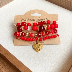 Close-up of four red beaded bracelets with a gold heart pendant on a display card