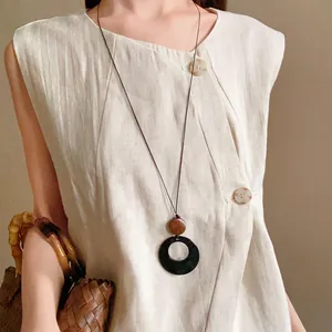 Vintage ethnic style long necklace featuring a large black circular pendant on linen