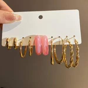 Detailed view of gold-tone and pink marbled hoop earrings set on a white display card