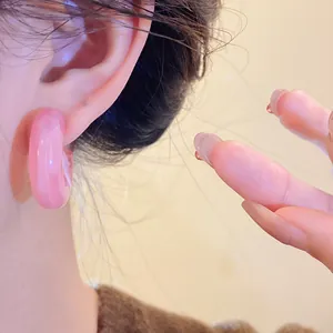 Close-up view of pink resin hoop earring worn on ear, showing translucent texture