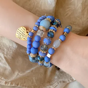 Macro detail of blue beaded bracelet with gold heart charm engraved with I love you