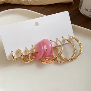 Close-up view of elegant gold hoop and pink resin earring set on a display card.