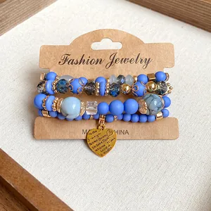 Detailed view of multi-layer blue beaded bracelets featuring a golden heart charm