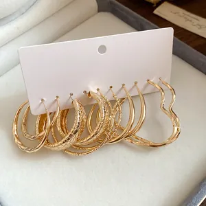 Close-up of varied gold hoop earrings set including heart and textured designs.