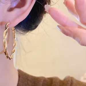 Detailed close-up of elegant gold twisted hoop earrings worn on an ear for a minimalist look