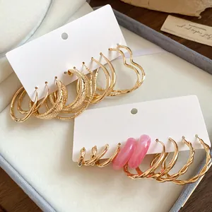 Close-up of gold-plated hoop earrings set with pink resin accents on white cards