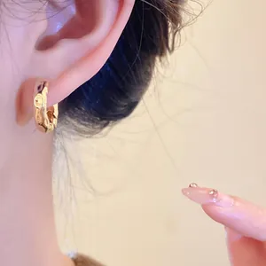 Detailed close-up showing the textured surface of elegant gold hoop earrings on ear