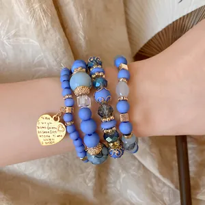 Detailed macro shot of a multi-layer blue beaded bracelet featuring a gold heart charm