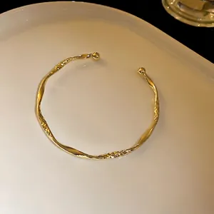 Elegant gold twisted geometric open bangle with a textured hammered finish for women