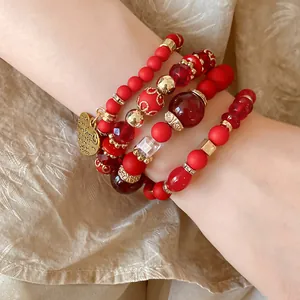 Detailed close-up of elegant red and gold beaded bracelets with engraved heart pendant
