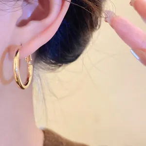 Detail view of elegant minimalist gold hoop earrings with silver needle worn on ear