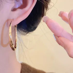 Close-up detail of stylish gold twisted hoop earrings worn for a retro elegant look