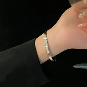 Close-up of elegant silver twisted wavy open bangle on woman's wrist with black sleeve