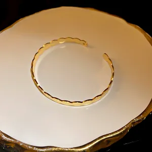 Macro detail of the gold-toned scalloped edge on this minimalist open cuff bracelet
