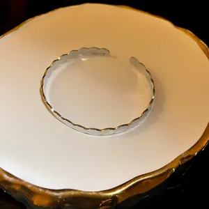 Close-up of a minimalist silver open bangle with elegant scalloped edge design and shine