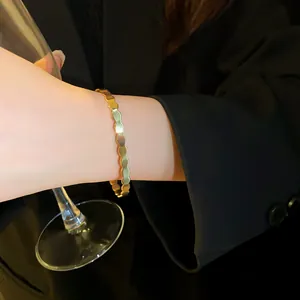 Elegant close-up of a gold wavy geometric open bangle bracelet worn with a black blazer.