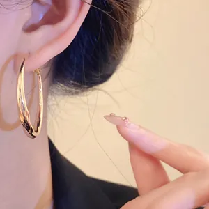 Detailed close-up view of a large twisted gold hoop earring worn by a female model