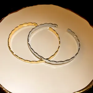 Close-up of wavy gold and silver minimalist open cuff bracelets on decorative plate