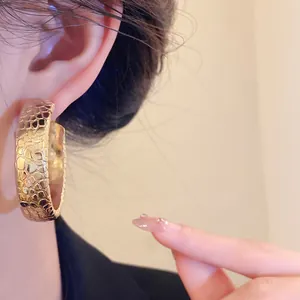 Detailed view of vintage gold hoop earrings with unique texture worn by model for luxury look