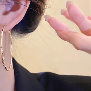 Detailed close-up showing the intricate texture of a gold-toned fashion hoop earring