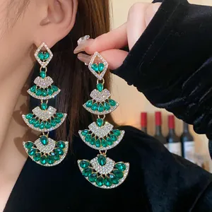 Dettaglio di eleganti orecchini a ventaglio con strass verde smeraldo e perni in argento puro.