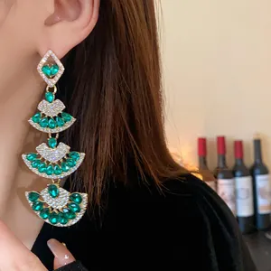 Primo piano di orecchini vintage a ventaglio verde smeraldo indossati da una modella.