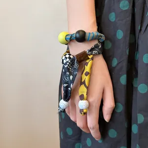 Vista dettagliata di un bracciale bohémien in tessuto con trame miste e perline