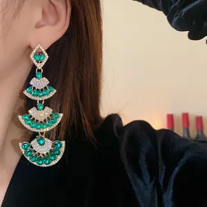 Primo piano di orecchini a nappa verdi a forma di ventaglio con cristalli color smeraldo