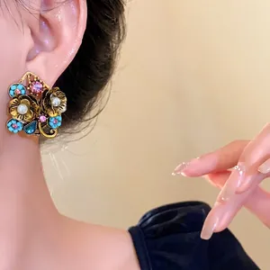 Orecchini vintage a fiori con cristalli colorati e perle indossati da una modella asiatica