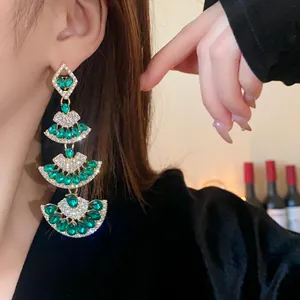 Primo piano di orecchini vintage a forma di ventaglio con strass verdi su una modella