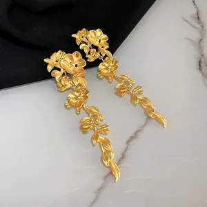 Vintage matte gold floral leaf tassel drop earrings on marble and black fabric background