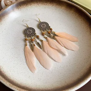 Detailed macro view of bohemian feather tassel earrings in a rustic ceramic bowl