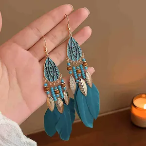 Detailed view of bohemian teal feather tassel earrings with gold tribal accents