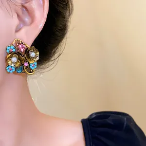 Primo piano di orecchini floreali vintage con perle e strass colorati su una modella