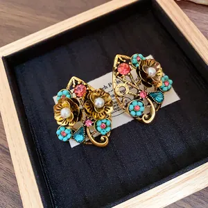 Primo piano di orecchini vintage a fiore dorato con strass rosa e perle turchesi
