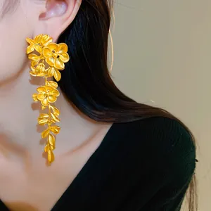 Elegant macro view of long gold flower and leaf tassel earrings with vintage textured finish