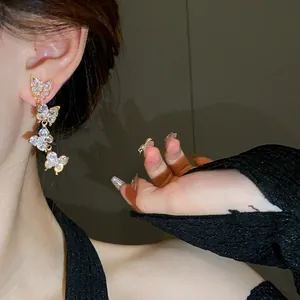 Close-up detail of elegant zircon butterfly tassel earrings with silver needles.