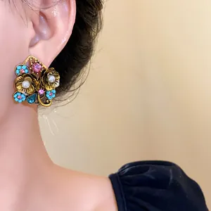 Primo piano di orecchini a fiore vintage con perle e strass colorati sull'orecchio