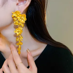 Detailed close-up of golden vintage floral tassel earrings on model