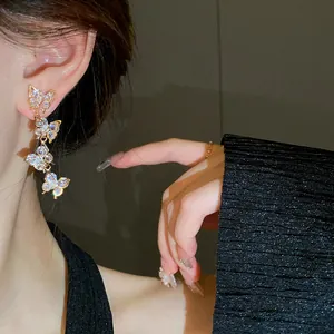 Close-up detail of elegant sparkling zircon butterfly tassel earrings worn by a model
