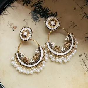 Detail view of vintage bohemian gold hoop earrings with white pearls and sun motifs