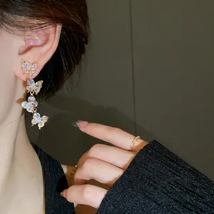 Close-up of sparkling zircon butterfly drop earrings worn by an elegant model
