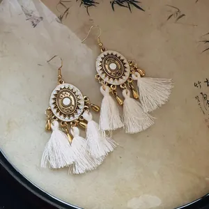 Detail shot of Bohemian retro gold-tone earrings with white tassels and mandala design
